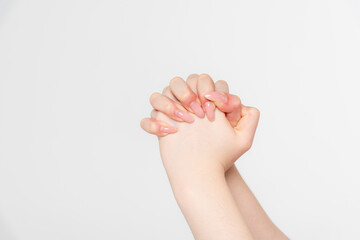 Close-up side view of elegant female hands holding each other against grey background. Soft focus....