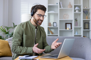 Man with a headset conducting a virtual business meeting from home, sitting on a couch with a...