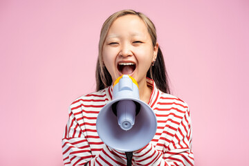 Asian girl making announcement with megaphone in hands, looking at camera, isolated