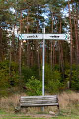 zurück und weiter - Wegweiser hinter einer alten Sitzbank - deutsch