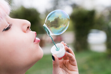 happy beautiful young woman blowing soap bubbles outdoor