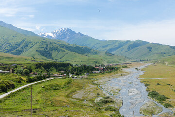 Mountain river of the village of Dargavs. Beautiful panorama of green alpine meadows, hills and...