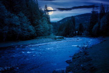 river flows through the valley of carpathian mountains at night. shallow water reveals stones. synevyr national park of ukraine in full moon light
