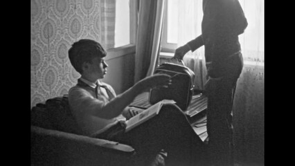Archive film pioneer teenage boys together in Soviet apartment indoor. Polite friendly communication between school best friends. Vintage intelligent childhood lifestyle. Retro black white 1980s movie