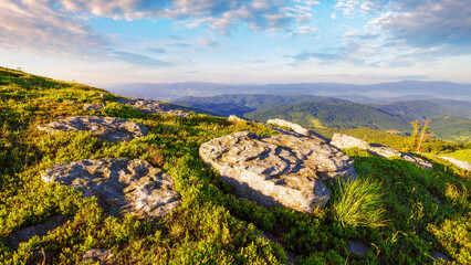 stone on the grassy hillside at sunrise. view in to the distant valley of carpathian mountains....