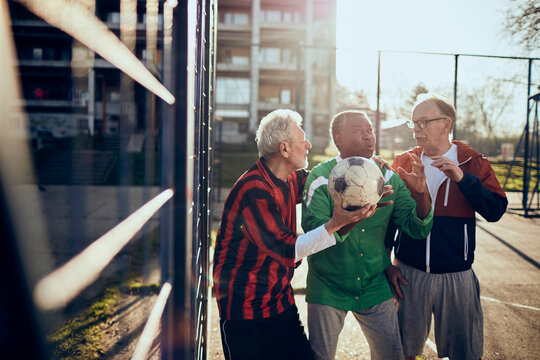 Senior friends discussing soccer tactics at a community sports field