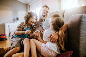 Happy father playing with son and daughter at home