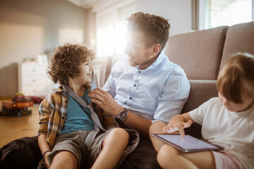 Happy father playing with son and daughter at home