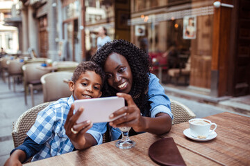 Black mother and son taking a selfie at a cafe