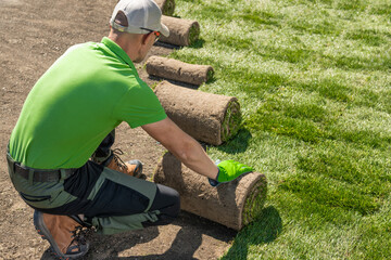Man Installing Grass Turfs Inside Backyard Garden.