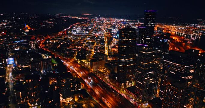 Amazing illumination of night metropolis. Numerous cars go by the highways of Seattle, Washington State, the USA. Aerial view.