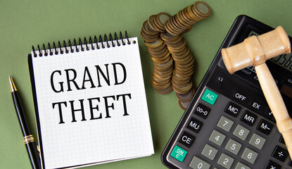 GRAND THEFT - words in a notepad against the background of a calculator and a judge's gavel