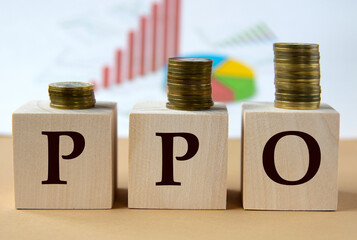 PPO- abbreviation on wooden balls on a background of coins and graphics.