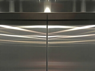 Shiny stainless steel elevator doors reflecting inside ceiling lights