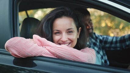 Smiling woman looking out the open window of car next to man. Slow motion