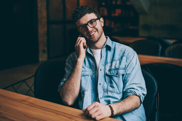 Portrait of happy cheerful hipster guy looking at camera and consulting with colleague vie...