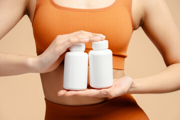 Closeup of fitness woman holding bottle with vitamins, capsules or pills and standing isolated