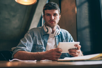 Handsome hipster guy in trendy apparel waiting email from work on digital tablet, portrait of...