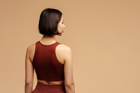 Back view of the young woman in sportive clothes standing over isolated