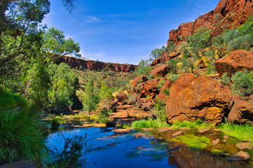 Landscape with red rocks, deep blue water and green trees in the spectacular Dales Gorge, Karijini National Park, Western Australia. 
