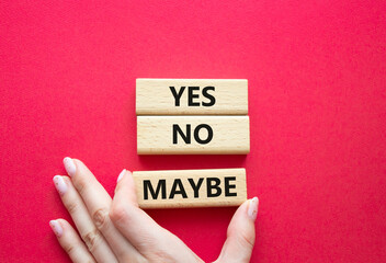 Yes No Maybe symbol. Concept word Yes No Maybe on wooden blocks. Beautiful red background. Businessman hand. Business and Yes No Maybe concept. Copy space.