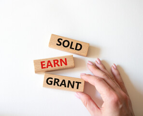 Sold Earn Grant symbol. Concept words Sold Earn Grant on wooden blocks. Businessman hand. Beautiful white background. Business and Sold Earn Grant concept. Copy space.