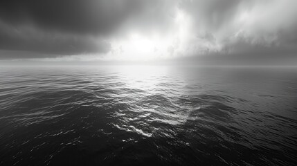Obraz premium Dramatic Monochrome Seascape with Glistening Ocean Water under Piercing Sunbeams Breaking Through Moody Clouds