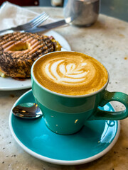 Lunch break. Coffee and Bagel with meat and cheese. Healthy lunch. Latte art coffee in a blue turquoise mug with saucer. Side view.