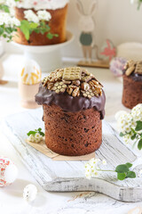 Festive Easter cake adorned with chocolate glaze and golden walnuts on a rustic wooden board.