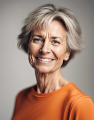 Fototapeta premium Portrait of a smiling middle-aged woman with orange tshirt standing against white background 
