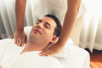 Caucasian man customer enjoying relaxing anti-stress spa massage and pampering with beauty skin recreation leisure in day light ambient salon spa at luxury resort or hotel. Quiescent