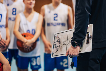 Close up of basketball coach holding clipboard on training with juniors