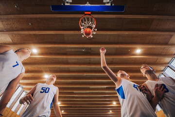 Low angle view of junior basketball players at the hoop making a score