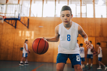 Close up of a basketball kid in action dribbling a ball at indoor court - Powered by Adobe