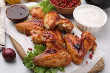 Fresh marinated chicken wings, spices and lettuce on light table, closeup