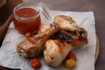 Marinade, roasted chicken drumsticks and tomatoes on brown table