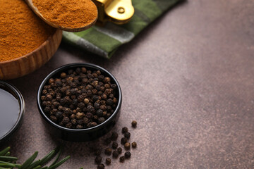 Aromatic peppercorns and different fresh ingredients for marinade on brown table. Space for text