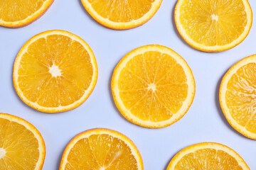 Slices of juicy orange on light blue background, flat lay