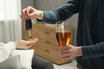 Man with glass of alcoholic drink giving car key to woman, closeup. Don't drink and drive concept