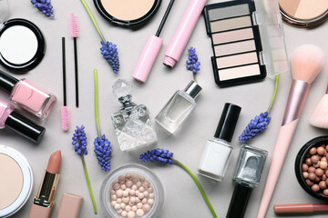 Flat lay composition with different makeup products and beautiful spring flowers on gray background