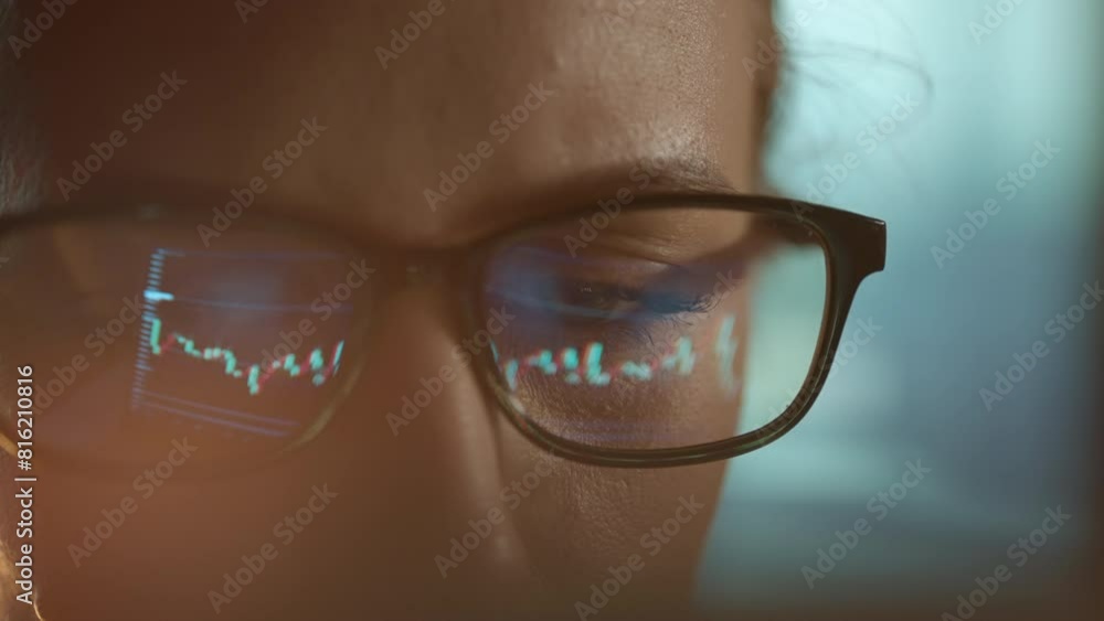 Poster trader wearing glasses is working on laptop computer. screen with stock market charts and bitcoin bt