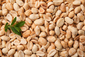 Many fresh peeled peanuts and leaves as background, top view