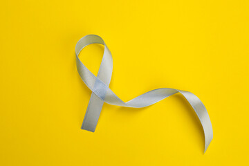 International Psoriasis Day. Ribbon as symbol of support on yellow background, top view