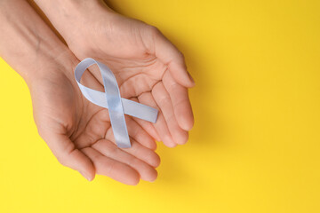 International Psoriasis Day. Woman with light blue ribbon as symbol of support on yellow...