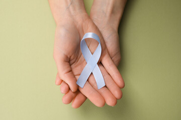 International Psoriasis Day. Woman with light blue ribbon as symbol of support on green background,...