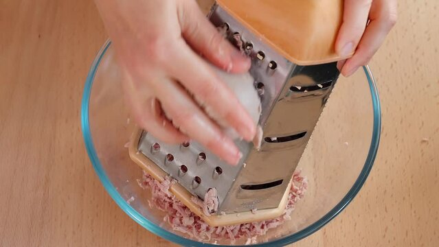 Grate the ham into a glass bowl for the filling. Ham filling for toast. Appetizers with ham. Close-up, macro, top view