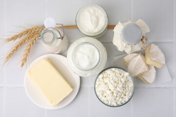 Different dairy products and spikes on white tiled table, flat lay