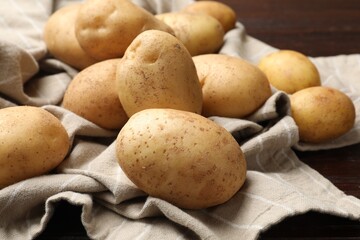 Raw fresh potatoes and napkin on wooden table, closeup