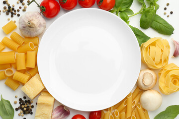 Plate surrounded by different types of pasta, products and peppercorns on white background, flat...