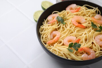 Tasty spaghetti with shrimps and parsley in bowl on light tiled table, closeup. Space for text